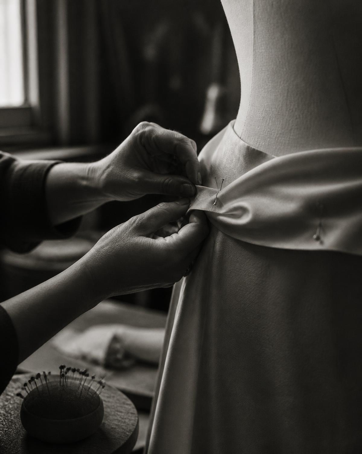Hands pinning a hem in the atelier